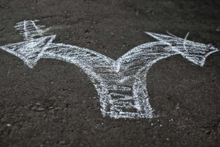 Arrows drawn with chalk on the pavement concept difficult choices composed in lifeの写真素材