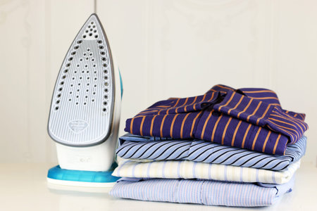 pile of mans ironing shirts in a stack and handの写真素材