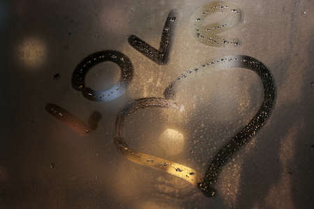 word love on the glass with drops indoor in winter eveningの写真素材