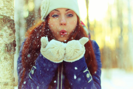 Pretty red-haired girl in the winter forest walks in the snow on a sunny day