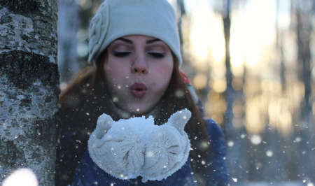 Pretty red-haired girl in the winter forest walks in the snow on a sunny dayの写真素材