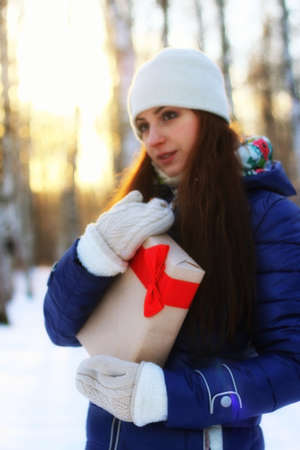 Pretty red-haired girl in the winter forest walks in the snow on a sunny dayの写真素材