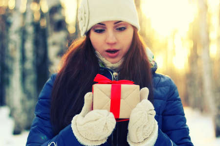 Pretty red-haired girl in the winter forest walks in the snow on a sunny dayの写真素材