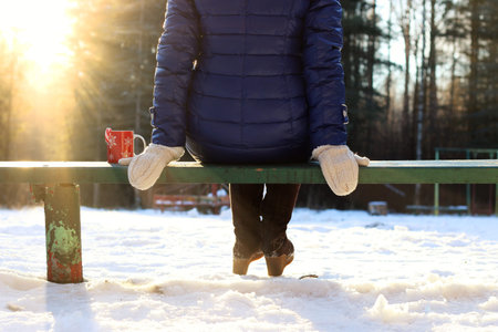 Pretty red-haired girl in the winter forest walks in the snow on a sunny dayの写真素材