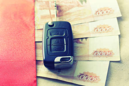 Black keychain car key on a matt black background and moneyの写真素材