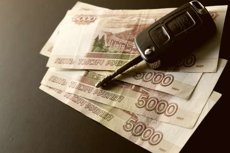 Black keychain car key on a matt black background and moneyの写真素材