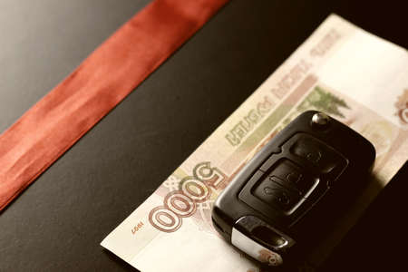 Black keychain car key on a matt black background and moneyの写真素材