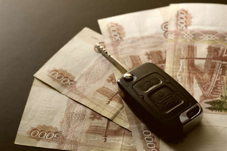 Black keychain car key on a matt black background and moneyの写真素材