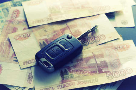 Black keychain car key on a matt black background and moneyの写真素材