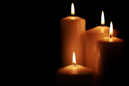 bright flame of a burning candle on a black background on the eve of New Year holidaysの写真素材