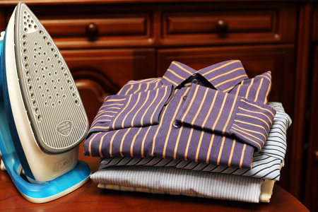 pile of mans ironing shirts in a stack and handの写真素材