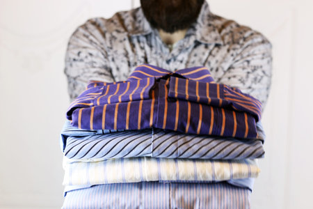 pile of mans ironing shirts in a stack and handの写真素材