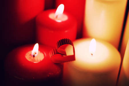 many candles of different sizes and colors on a brown tableの写真素材