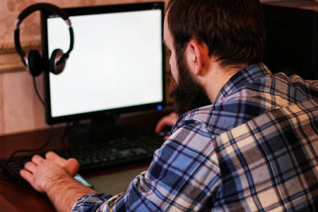 bearded man sitting at a table and working with a laptop