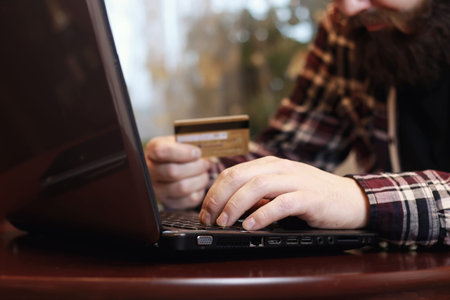 bearded man sitting at a table and working with a laptop