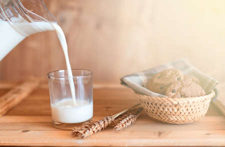 glass and carafe with fresh cow milk on a wooden tableの写真素材