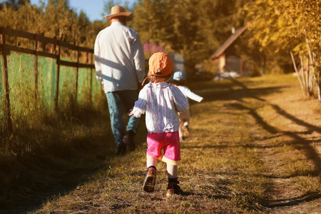 young grandfather bringing up grandchildren on his country area on a summer eveningの写真素材