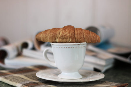 breakfast French-style hot coffee and fresh croissant and a soft pile of glossy magazines on the...