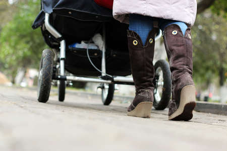 Autumn walk on the cobblestones of the parent in the park with a pramの写真素材