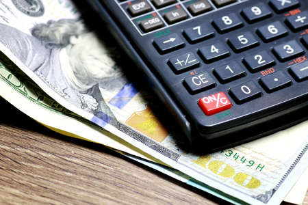 gray business calculator on a wooden table and a stack of money for the calculation of the amount of utility bills paymentの写真素材