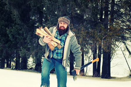 bearded handsome man went into the forest with an ax to produce wood for the furnaceの写真素材