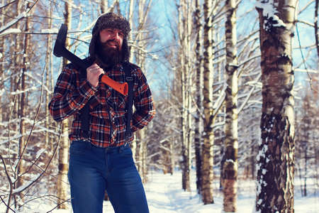 bearded handsome man went into the forest with an ax to produce wood for the furnaceの写真素材