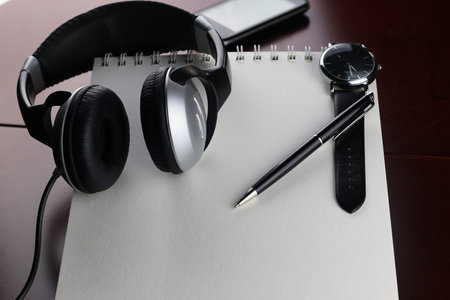 Headphones on a table next to the tablet and a clock