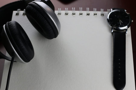 Headphones on a table next to the tablet and a clockの写真素材