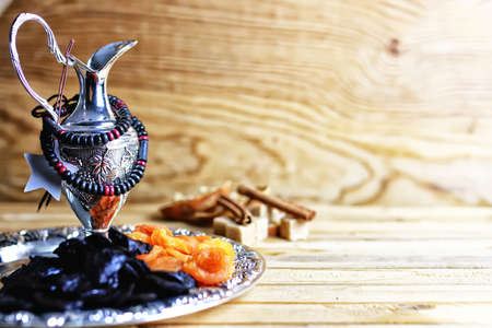 Dried oriental fruit on a silver tray on a wooden table lightの写真素材