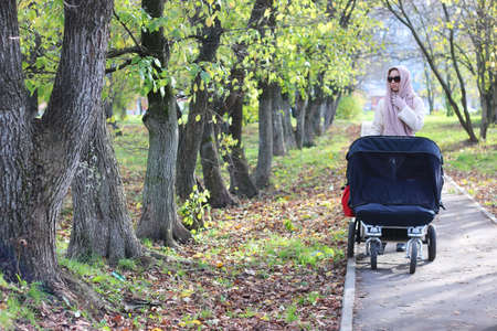 a pretty girl of European appearance in fashionable autumn clothing walking in the parkの写真素材