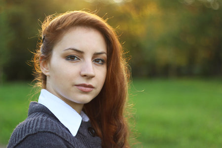 pretty young woman posing on camera in autumn park