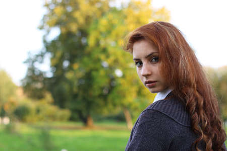 pretty young woman posing on camera in autumn parkの写真素材