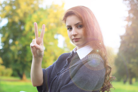 pretty young woman posing on camera in autumn parkの写真素材