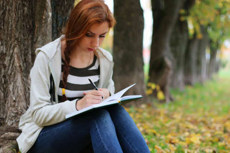 Pretty cute young girl walking in golden autumn parkの写真素材