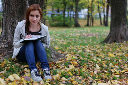 Pretty cute young girl walking in golden autumn parkの写真素材