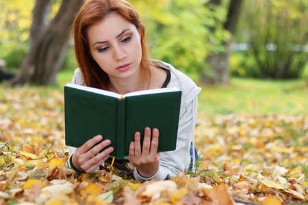 Pretty cute young girl walking in golden autumn parkの写真素材