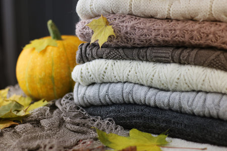 autumn concept pile of warm sweaters on a table and a cup of hot coffee