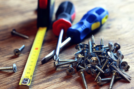 long silver screws and screwdriver on a wooden table textural joinery