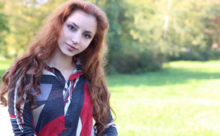 pretty young woman posing on camera in autumn parkの写真素材