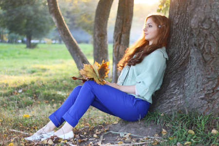 pretty young woman posing on camera in autumn parkの写真素材