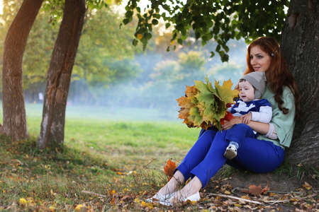 redhead girl with son Autumn park with falling leavesの写真素材