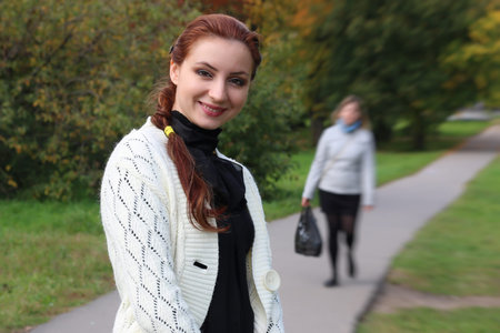pretty young woman posing on camera in autumn park