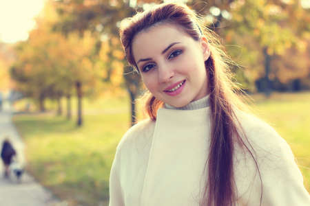 a pretty girl of European appearance in fashionable autumn clothing walking in the parkの写真素材
