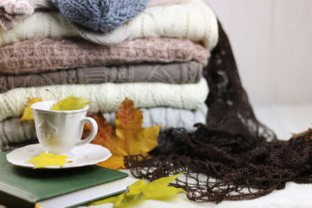 autumn concept pile of warm sweaters on a table and a cup of hot coffeeの写真素材