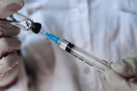 health worker dials the vaccine into a syringeの写真素材