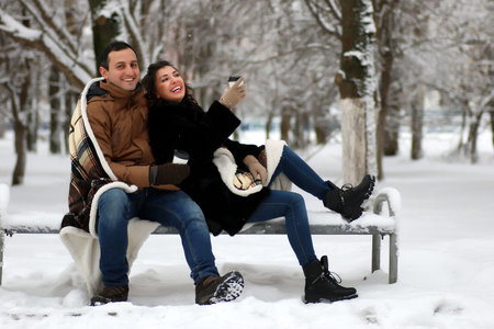 beautiful young couple in a snowy park wrapped in a warm plaid walks