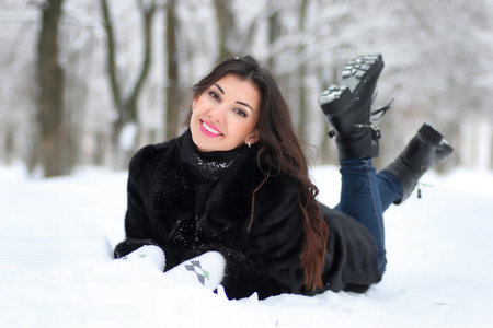 beautiful young woman walking in winter snow-covered parkの写真素材