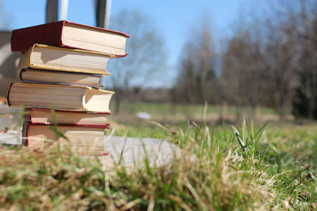 books standing different objects on a wooden table on a background of blurred summer foliageの写真素材