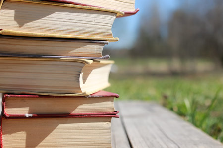 books standing different objects on a wooden table on a background of blurred summer foliageの写真素材
