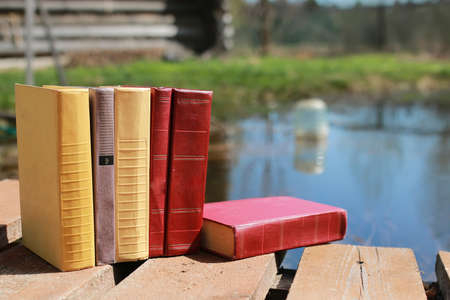 books standing different objects on a wooden table on a background of blurred summer foliageの写真素材